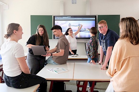Schüler der Ev. Fachschule für Sozialpädagogik vor einer digitalen Tafel. Sie machen Gruppenarbeit.