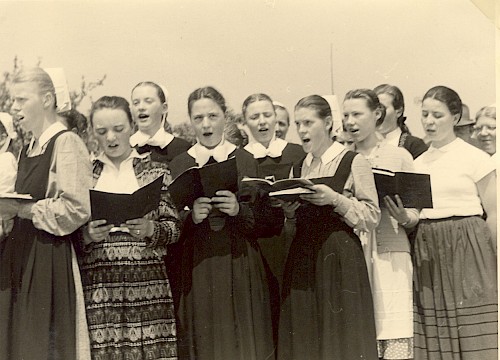 1955 – der Schülerinnenchor singt bei einem Fest Eine historische Aufnahme von 1955 in schwarz-weiß zeigt den Schülerinnenchor singend bei einem Fest